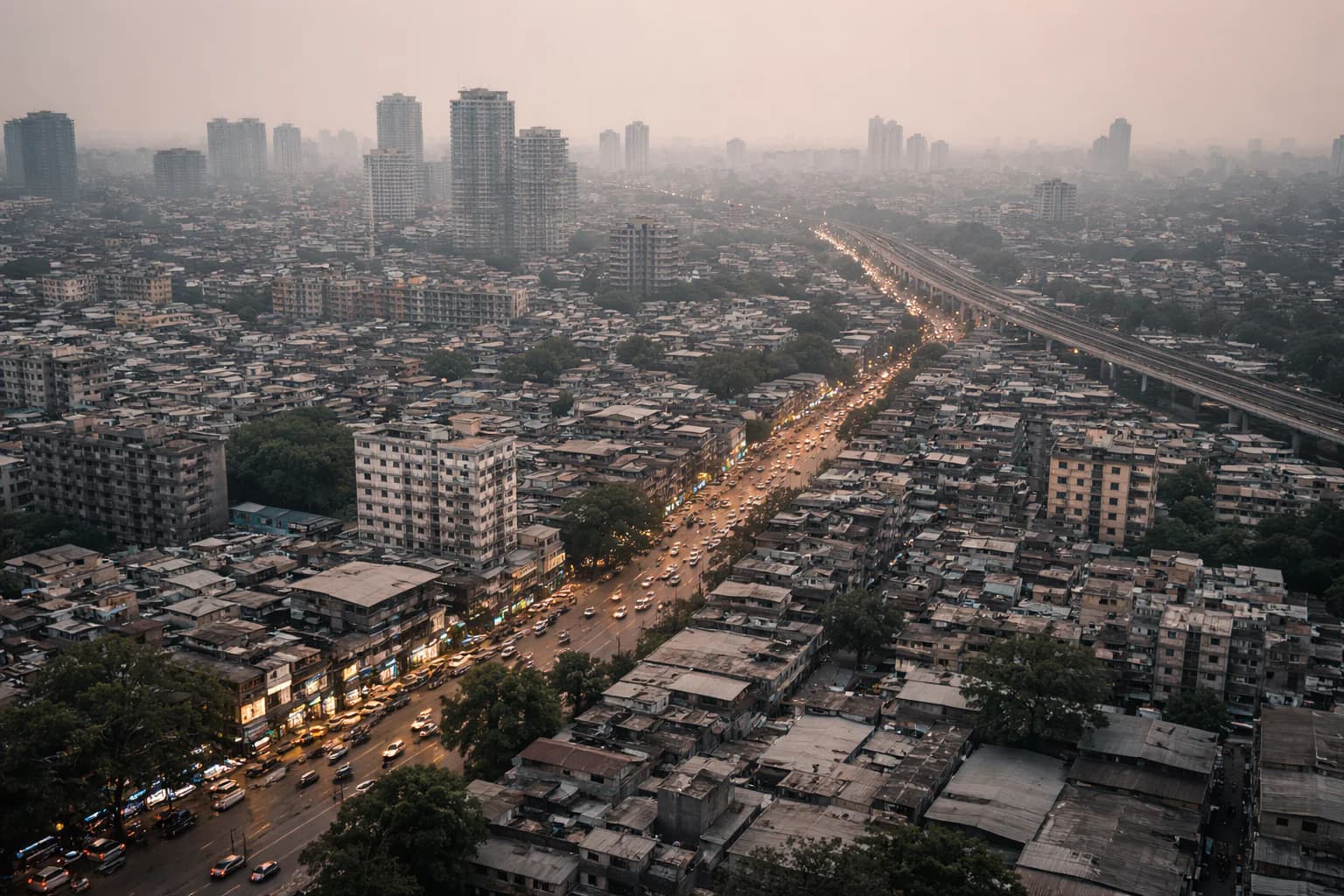 Aerial view of a dense Indian city at dusk with a lit highway cutting through the skyline